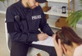 Police officer talking to robbery victim after burglary at home interrogating young upset woman. Royalty Free Stock Photo