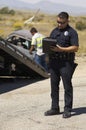 Police Officer Writing Notes At Car Crash Scene