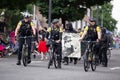 Police officers on bicycles riding along side anti cop masked demonstrators.