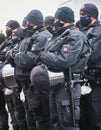 Police officers with black knitted caps and uniforms with batons hold their helmets with visors in their hands