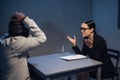 At the police station, a girl investigator interrogates a black guy who is sitting in front of her in handcuffs