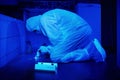 Police technician collecting DNA from stains under UV light