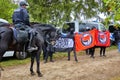 Policeman on a black horse stands in front of demonstrators carrying banners of Antifa