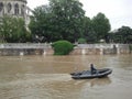 A policeman floats on a boat on a brown river. Europe. France. Flood in Paris. Seine river near Notre Dame de Paris.