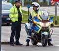 Policeman on motorcycle with flashing blue light and patrolman on foot talking at the roadside