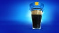 Policeman. Mug of frothy dark beer wearing police cap isolated over blue neon background. Concept of alcohol, drinks