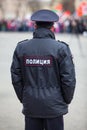 Policeman officer standing back to camera with inscription Police in Russian on uniform jacket