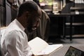 Policeman reading crime case file, analyzing photos on laptop Royalty Free Stock Photo