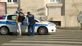 Policemen talking with their comrade sitting in car parked near station house