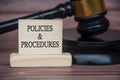 Policies and procedures text engraved on wooden block with gavel background. Policy and procedure concept