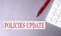 Policies Update text written on a gray background with pen and calculator