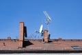 Red brick roof with chimneys and tv antennas on a clear blue sky Royalty Free Stock Photo