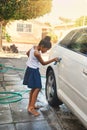 Polish, car and girl cleaning in driveway with water, soap and cloth at home. Happy kid, washing and vehicle at home for Royalty Free Stock Photo