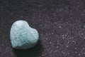 Polished amazonite stone in the shape of a heart on a black background