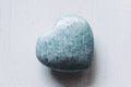 Polished amazonite stone in the shape of a heart on a white background