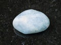 polished aquamarine (blue beryl) gem stone on dark