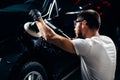 Car detailing - man with orbital polisher in auto repair shop. Selective focus. Royalty Free Stock Photo