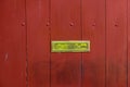 Polished brass mailbox slot on a painted wooden gate