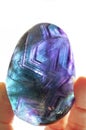 Fluorite crystal hand held in sunlight with bright purple and turquoise colors