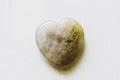 Polished fluorite stone in the shape of a heart on a white background