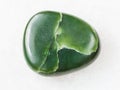 polished green nephrite gemstone on white marble