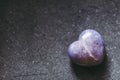 Polished lepidolite lilac stone in the shape of a heart on a black background