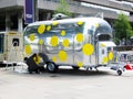 Polished metal vintage car trailer. A man decorates the trailer with yellow circles.UK. LONDON - May 26, 2018