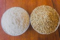 Polished and paddy or unhusked rice in two plate close up on wooden