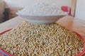 Polished rice in plate on top of big plate of paddy or unhusked rice