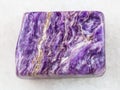 polished slab of charoite gemstone on white marble