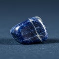 A polished sodalite stone rests on a surface, displaying its deep blue color with Royalty Free Stock Photo