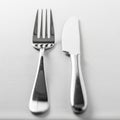 Steel fork and knife are placed side by side on a neatly arranged white Royalty Free Stock Photo