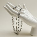 A polished, white ceramic hand mannequin serves as a display for a silver chain with Royalty Free Stock Photo