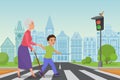 Polite little boy helps smiling old woman to pass the road at a pedestrian crossing while the green light shines