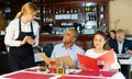 Polite waitress taking order from couple in pizza restaurant Royalty Free Stock Photo