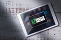 Top view of digital tablet on wood desk with online voting on screen. Royalty Free Stock Photo