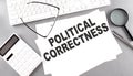 POLITICAL CORRECTNESS text on paper with keyboard, calculator on grey background