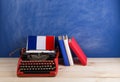 Political, news and education concept - red typewriter, flag of the France, books on table