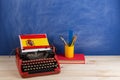 Political, news and education concept - red typewriter, flag of the Spain, book and stationery on table