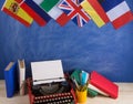 Political, news and education concept - red typewriter, flags of Spain, France, Great Britain and other countries, books,