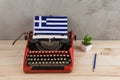 Political, news and education concept - red vintage typewriter, flag of the Greece, pencil