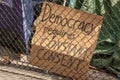 A political sign behind a fence states that Democracy requires constant consent