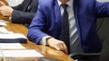 Politician or businessman sits at a table during a meeting next to documents and a folder. Work meeting with colleagues or