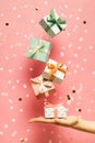 Polka dot pattern gift box with ribbon falling and female hands on pink background, levitation Royalty Free Stock Photo