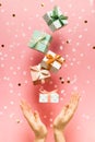 Polka dot pattern gift box with ribbon falling and female hands on pink background, levitation Royalty Free Stock Photo