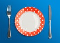 Polka dot red plate with fork and knife top view Royalty Free Stock Photo