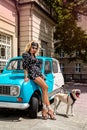 Polka dots fashion. Beautiful bLonde young woman near the car with dog.