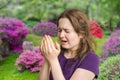 Pollen allergy concept. Young woman is going to sneeze. Flowers in background Royalty Free Stock Photo