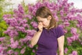 Pollen allergy concept. Young woman is sneezing. Flowering trees in background Royalty Free Stock Photo