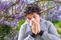 Pollen Allergy. Danger, Tennage boy sneezing in a flowers meadow. Concept: seasonal allergy.